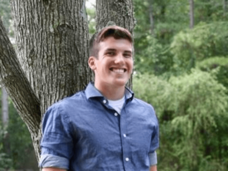 young man leaning on tree